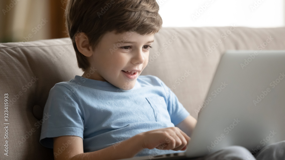 Small kid boy resting on couch, using educational app on laptop. Small kid boy resting on couch, using educational app on laptop.