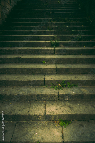 Breite Treppe in einem Park aus Naturstein mit Handlauf aus verrostetem Stahl im Dämmerlicht mit gruseliger und angsteinflößender Aura wie in einem Krimi photo