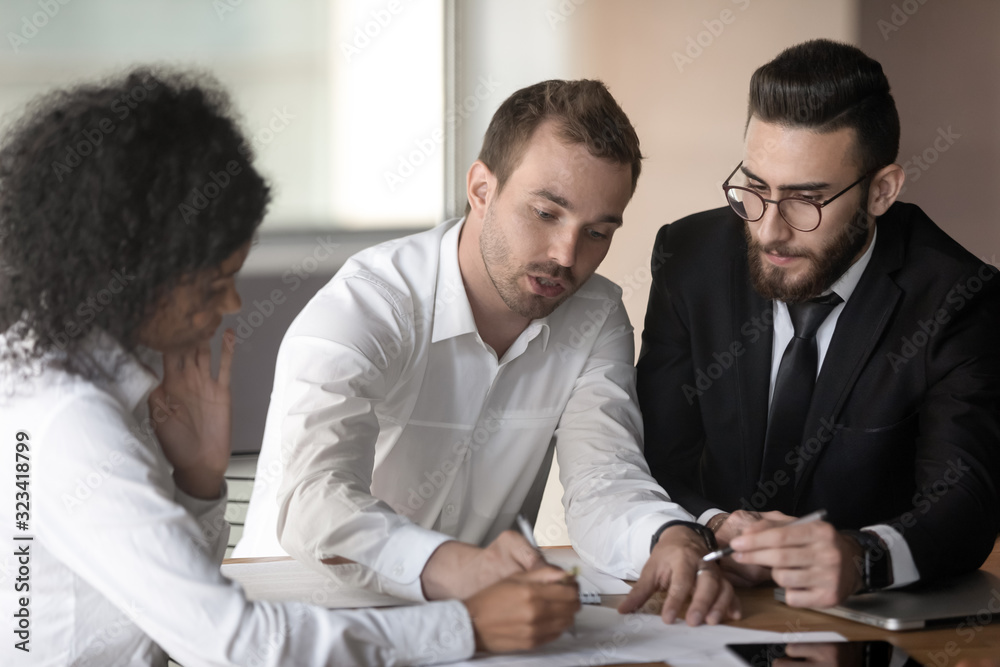 Diverse teammates working strategizing reviewing document together during meeting Diverse teammates working strategizing reviewing document together during meeting