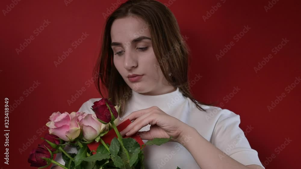 The concept of Valentine's Day and Women's Day. Girl holds a bouquet of roses and a note in her hand. A romantic gift The concept of Valentine's Day and Women's Day. Girl holds a bouquet of roses and a note in her hand. A romantic gift