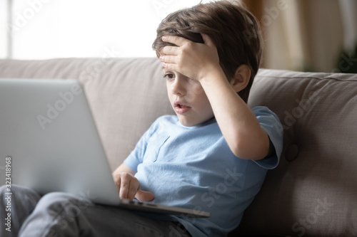 Little boy hocked by inappropriate content, looking at computer screen.