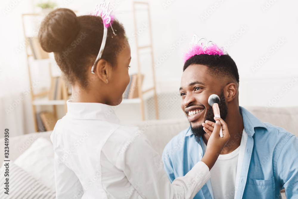 Little afro girl wearing crown and blushing father's cheeks Little afro girl wearing crown and blushing father's cheeks