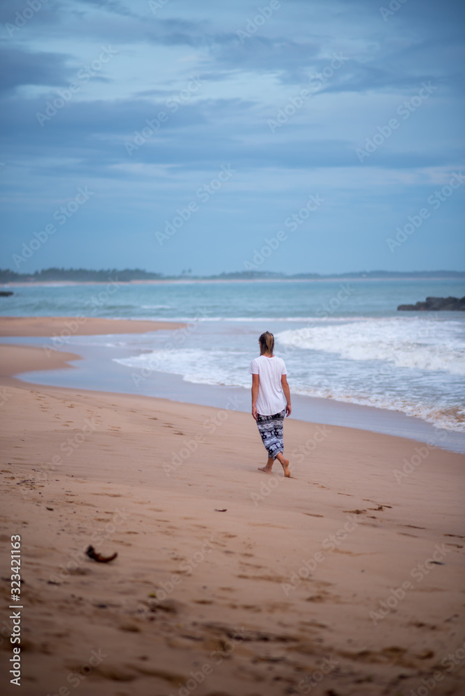 Tangalle, Sri Lanka : 2020 NOV 25 : Young Blonde woman walk the beach in Sunset in the beach of Tangalle, Sri Lanka.
