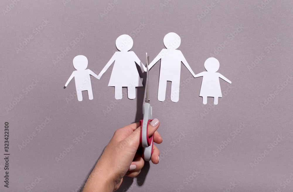Female hand cutting Paper family chain on gray background Female hand cutting Paper family chain on gray background