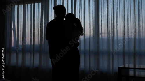 Silhouette of dancing couple against window