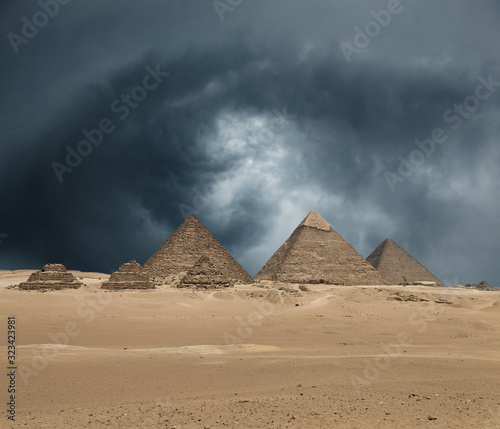 The Giza pyramid complex under dramatic grey stormy sky