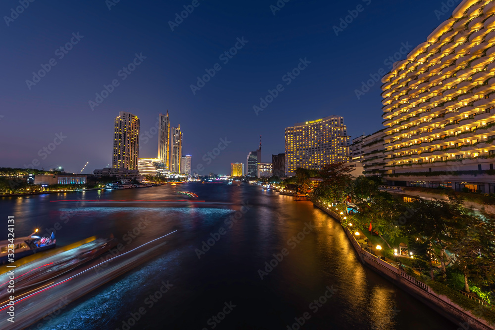 Obraz premium Skyscrapers and small traffic routes along the Chao Phraya River in Bangkok as seen from the Taksin Bridge at night. Bangkok, Thailand