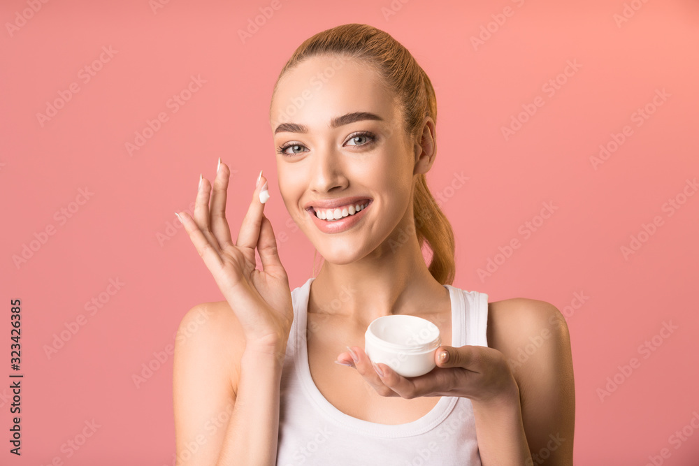 Girl Applying Facial Cream Holding Jar Standing On Pink Background Girl Applying Facial Cream Holding Jar Standing On Pink Background