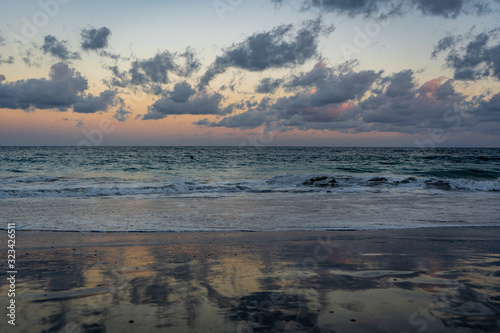 sunset at the beach with colorful clouds and waves