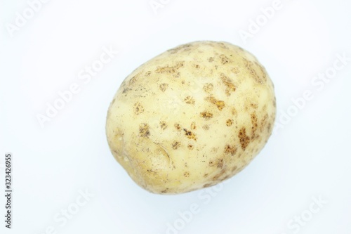 Unpeeled potatoes perched on a white background