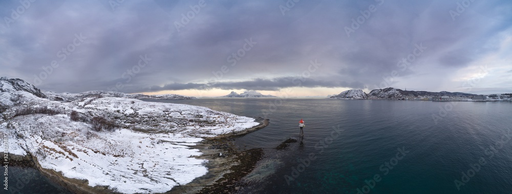 A view over the fjord west of the city of Bodø. A lantern at Hjertøya near Bodø city with a sign saying “Deadly cable, anchoring prohibited”. The island Landegode in the middle in the horizon.