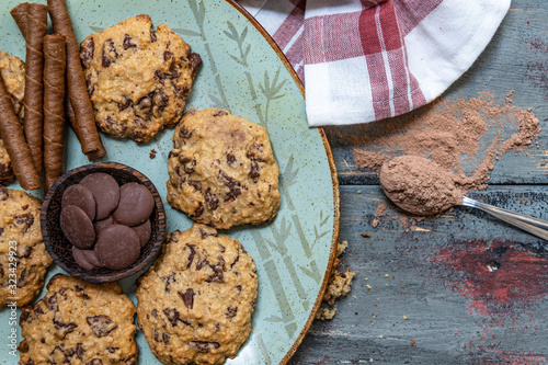 Chocolate cookies, on rustic wood next to cocoa in different forms