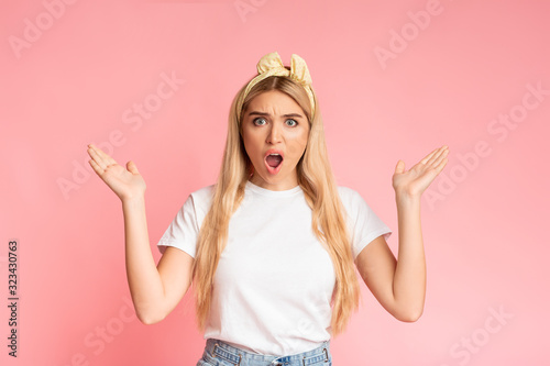Amazed teenage girl looking at camera spreading arms