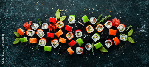 Big set of pieces of sushi rolls on black stone background. Top view. Free space for your text.