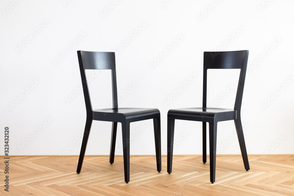 Obraz premium modern simplistic black chairs on a wooden flor in front of white background