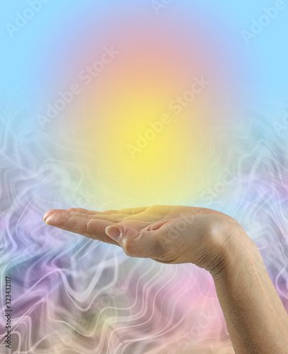 Focusing and Sending Golden Healing Energy - female open palm with a vivid yellow orange orb of energy against a blue graduated to energy flowing background with copy space