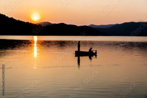 Silhouette of fishing at the sea with mountain and sunset © Suphansa