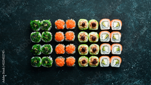 Big set of pieces of sushi rolls on black stone background. Top view. Free space for your text.