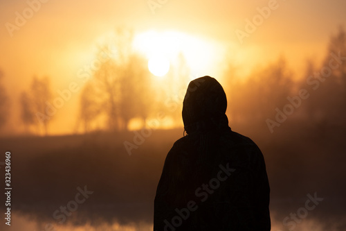 silhouette of man in foggy sunrise photo