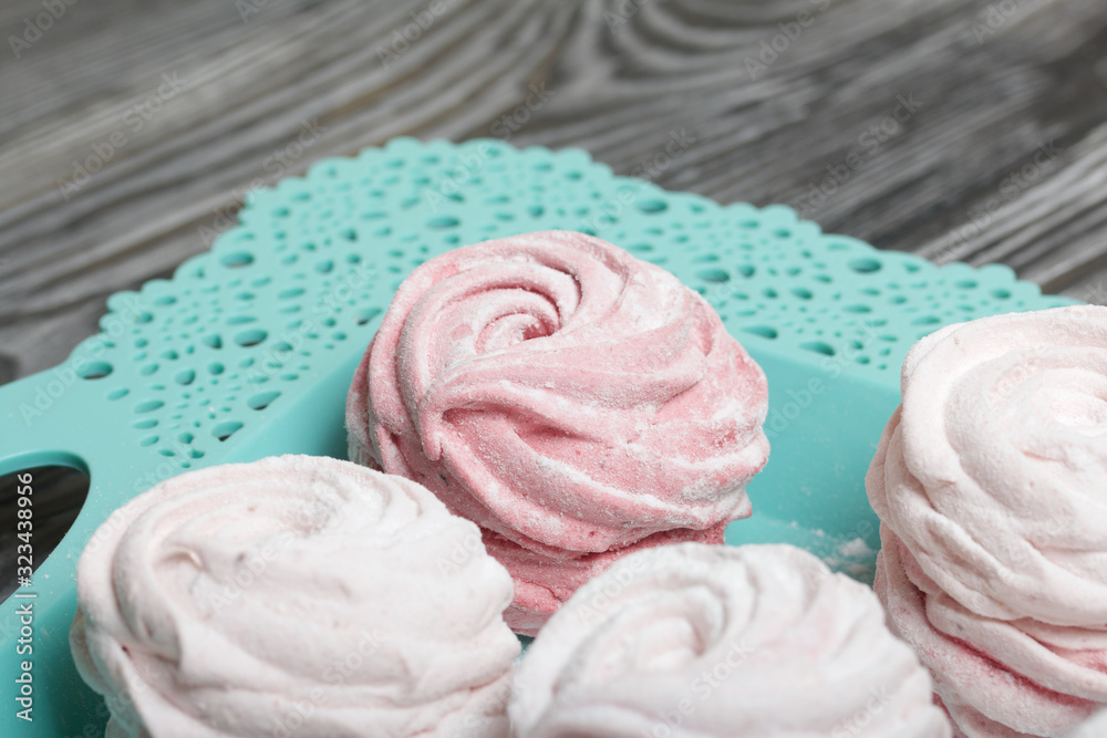 Delicate pink marshmallows of various shapes. Lies on a turquoise tray. Sprinkled with icing sugar. Delicate pink marshmallows of various shapes. Lies on a turquoise tray. Sprinkled with icing sugar.