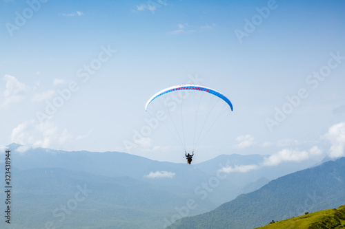 A tourist with an instructor flies a paraglider on the background of a beautiful mountain landscape. Extreme sports in the mountains.