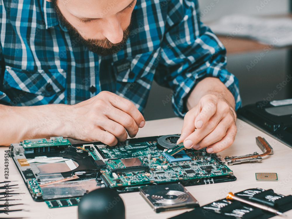 Naklejka premium Electronics repair shop. Disassembled laptop. Technician fixing computer components.