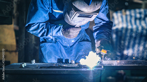 Factory worker in protectection mask using welder.