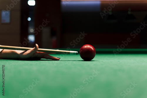 Close up at the girl aiming a cue ball on a ball in a pool table