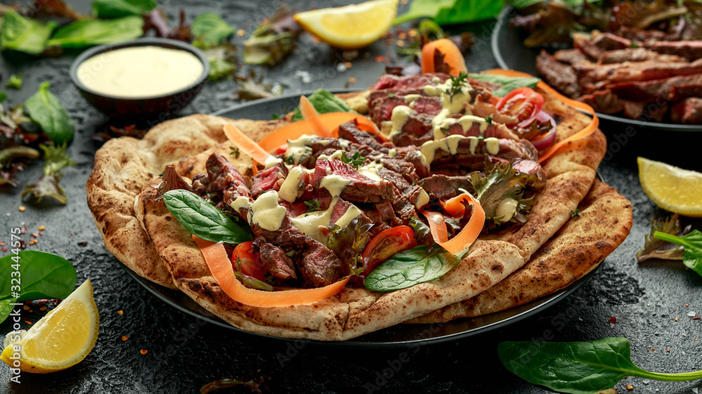 Grilled and sliced beef steak on garlic and coriander naan bread with carrot and spinach salad drizzled with home made mayonnaise sauce Grilled and sliced beef steak on garlic and coriander naan bread with carrot and spinach salad drizzled with home made mayonnaise sauce