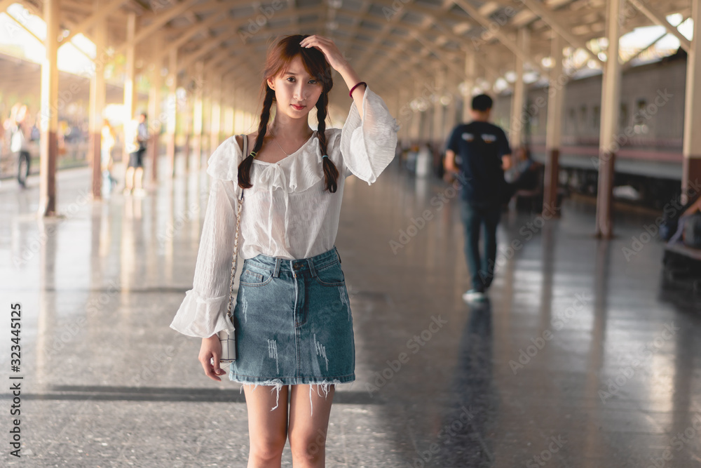 Asian young woman standing alone, Pretty girl smiles and happy for the holiday trip,Train station background and natural light, vintage style.