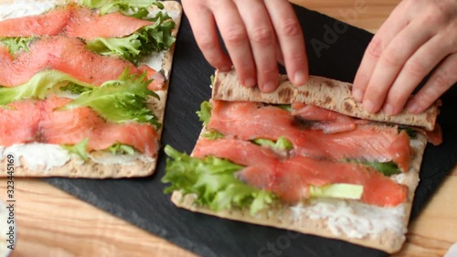 Woman making Swedish salmon, soft cheese, and lettuce roll for a lunchbox