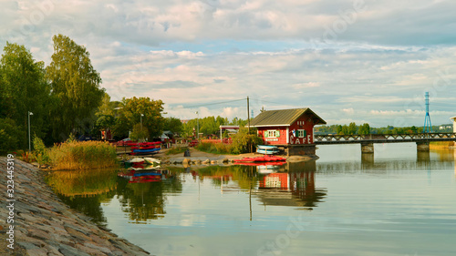 A small wooden cafe and a rental of water vehicles in Helsinki, near a small bridge over the bay.