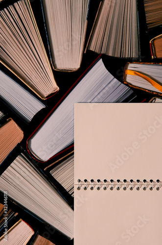 Lots of colourful thick open books stand on a dark background