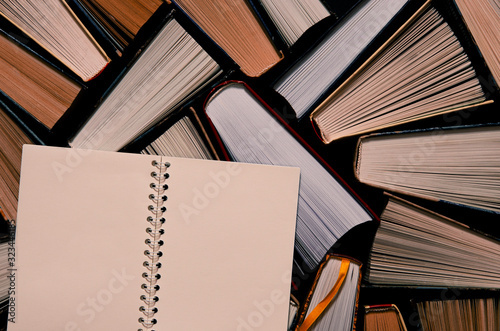 Lots of colourful thick open books stand on a dark background