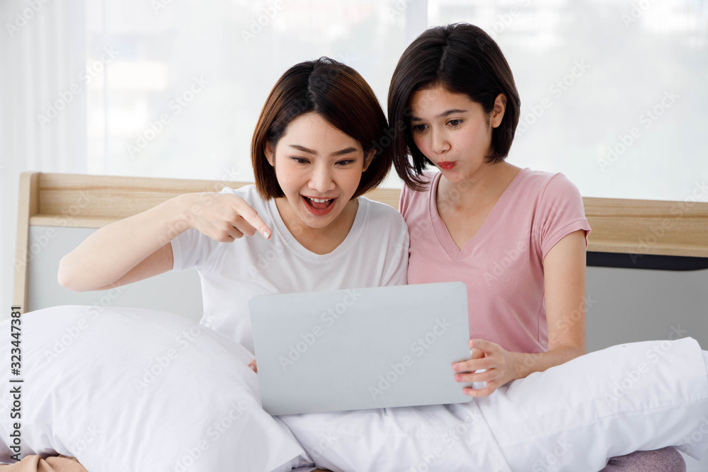 Two Asian women is very surprise while use their laptop during surf the internet. Concept for teenage or friends activity, lifestyle at home. Two Asian women is very surprise while use their laptop during surf the internet. Concept for teenage or friends activity, lifestyle at home.