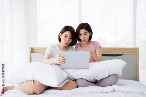 Two Asian women is very surprise while use their laptop during surf the internet. Concept  for teenage or friends activity, lifestyle at home.