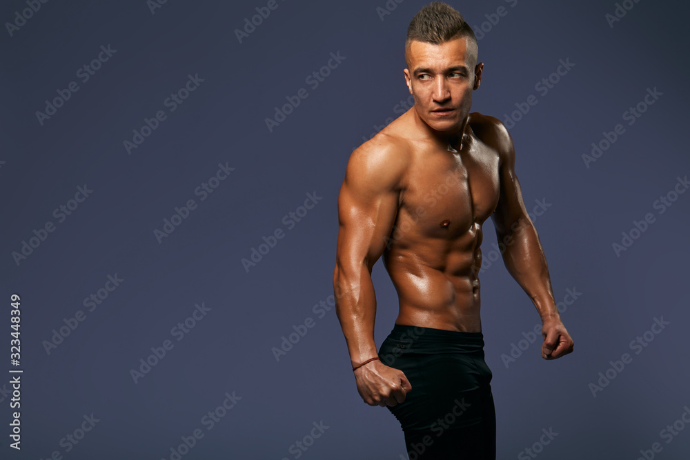 Fototapeta premium handsome sportsman demonstrating his ideal abs belly, guy showing his perfect healthy body, beauty, close up portrait, isolated blue background, studio shot, copy space