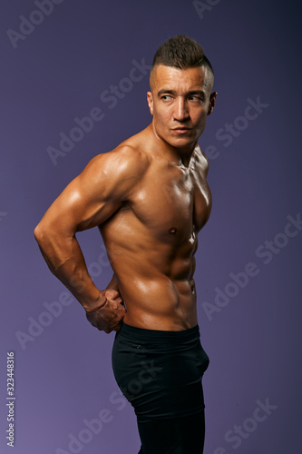 serious handsome athlete keeping his arms behind his back posing to the camera, close up portrait, isolated blue background, studio shot