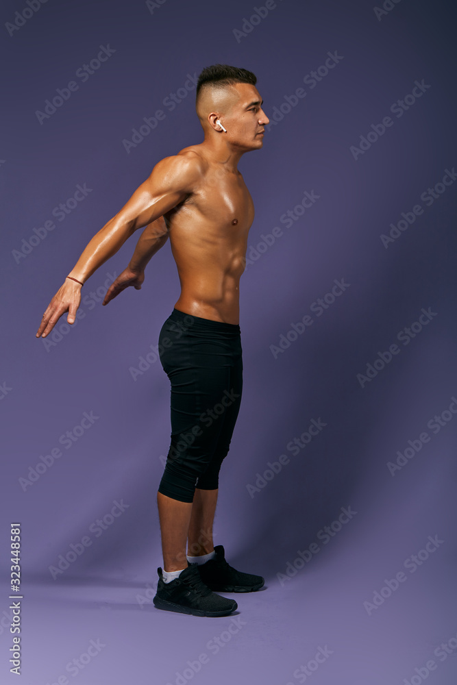 Muscular sexy athlete going to jump, guy doing warming up exercises before training, full length photo, isolated blue background, studio shot . Muscular sexy athlete going to jump, guy doing warming up exercises before training, full length photo, isolated blue background, studio shot .