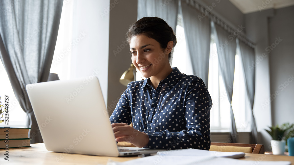 Happy young Indian female busy working on laptop Happy young Indian female busy working on laptop