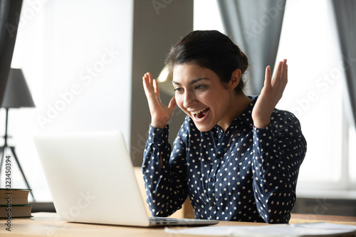 Excited indian girl amazed with good online news photo
