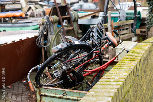 Gouda, South Holland/The Netherlands - February 15 2020: two old bikes left behind dumped in a container on a small salvage yard waiting to be recycled or repaired