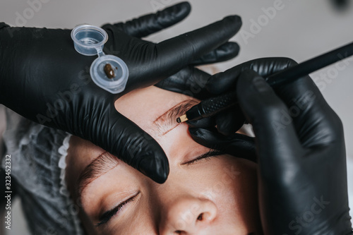 Eyebrows microblading concept. Cosmetologist preparing young woman for eyebrow permanent makeup procedure. photo