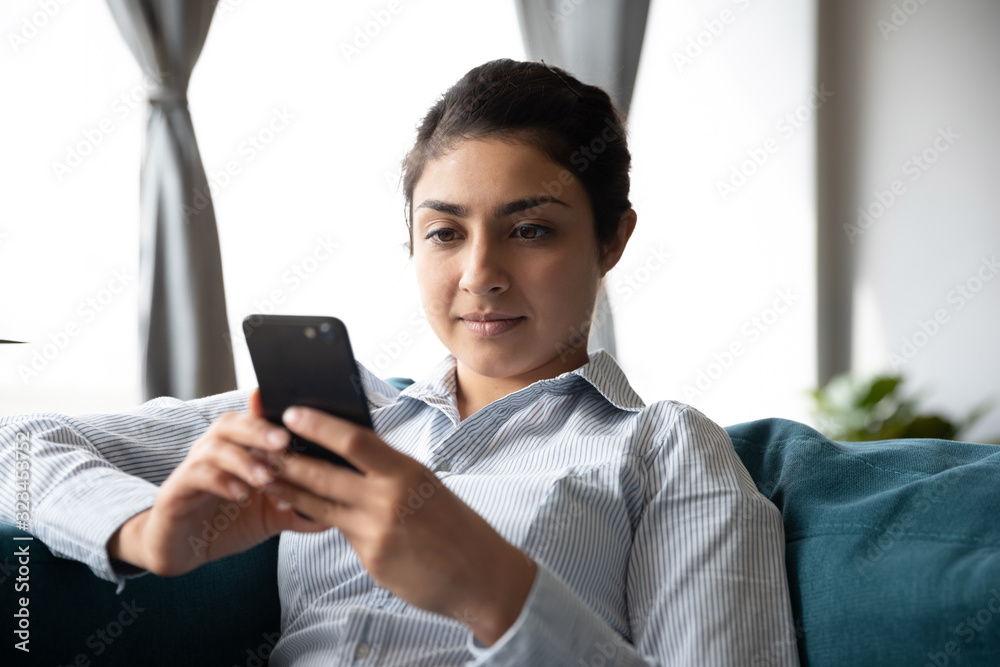 Millennial ethnic woman rest on couch using cellphone Millennial ethnic woman rest on couch using cellphone