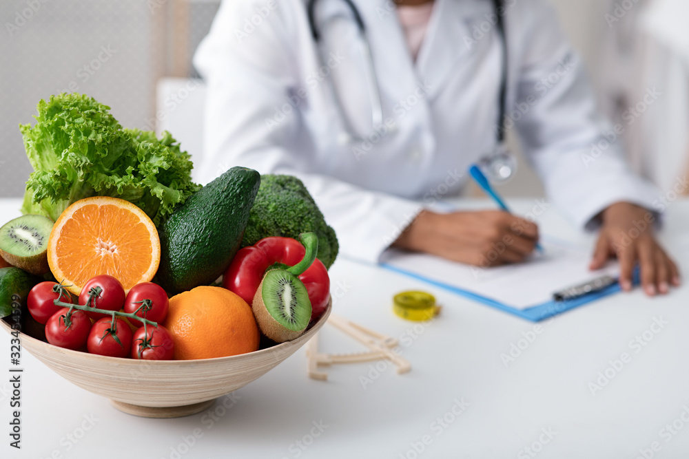 Afro lady nutritionist doctor writing vegetable diet plan