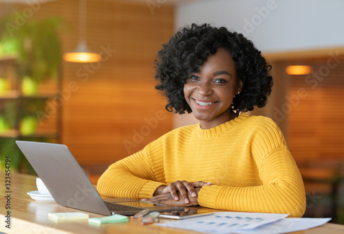 Cheerful black businesswoman working on marketing report