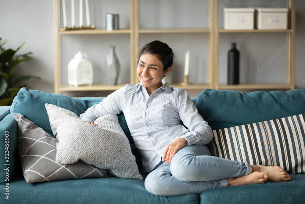 Happy millennial ethnic girl relaxing on sofa at home Happy millennial ethnic girl relaxing on sofa at home