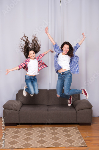 Celebrate womens day. Girls only. Mom and daughter friends. Mother cheerful daughter jumping couch. Happy childhood. Girls having fun. Kid and mom play together. Happiness fun. Girls power concept