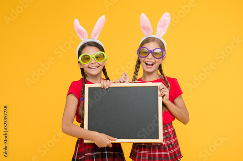 happy childhood concept. small girls bunny ears yellow background. funny little sister kids celebrate easter. egg hunt begin. traditional spring holiday. copy space. happy easter. spring is coming © be free