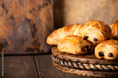 Canvas Print Freshly baked sweet buns puff pastry with chocolate and croissants on old wooden background
